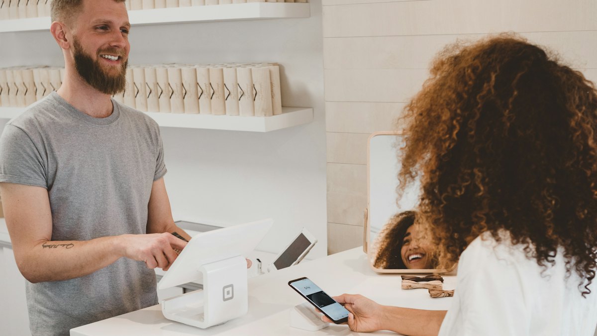 Commerçant souriant servant une cliente dans une boutique
