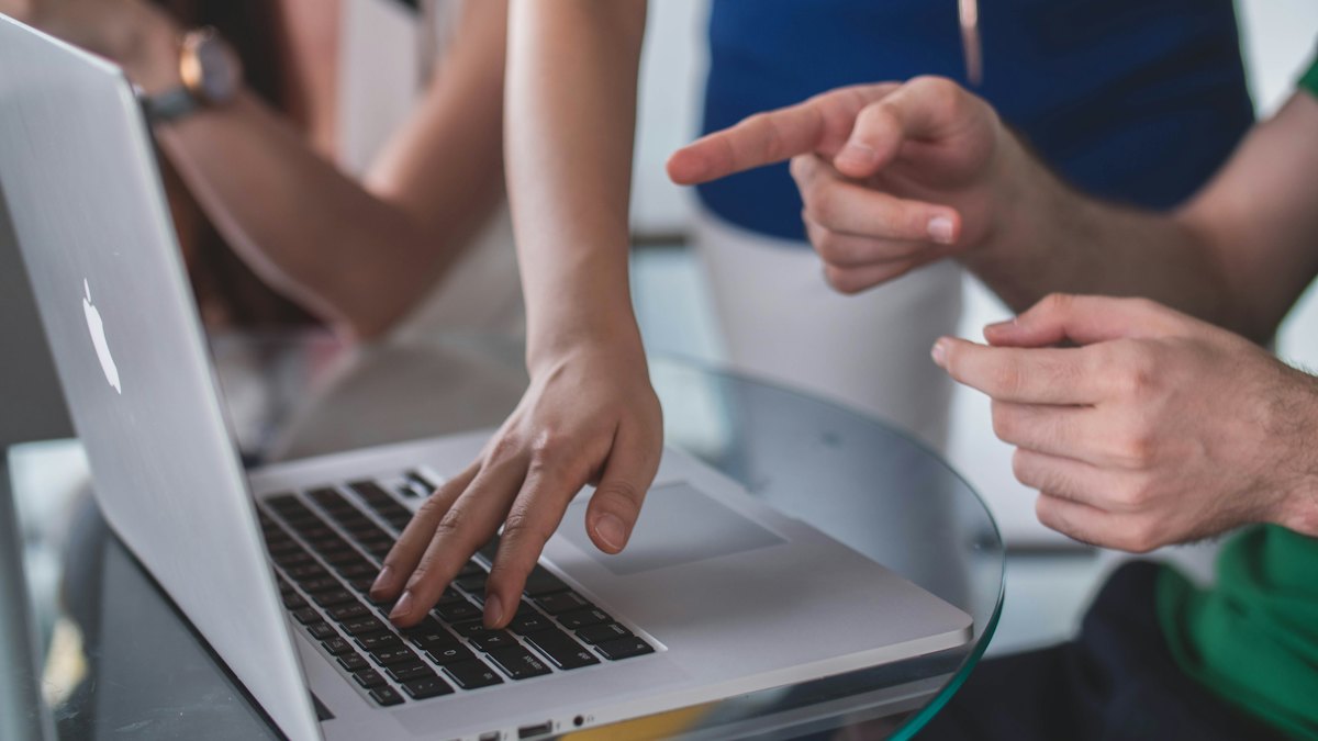 Personnes discutant et pointant l'écran d'un ordinateur portable