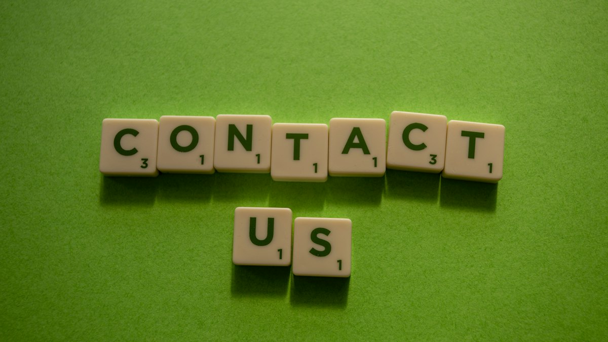 Lettres en bois formant les mots « contact us » sur un fond vert