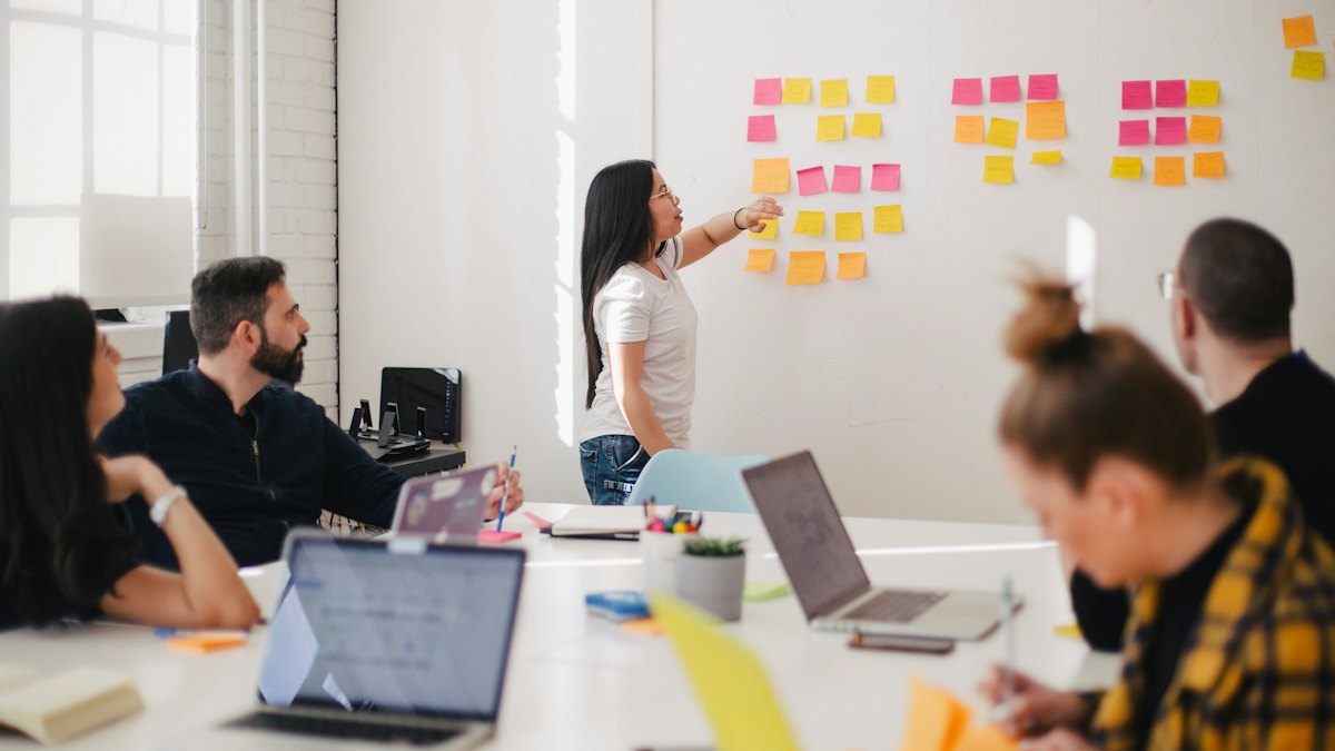 Équipe devant un tableau couvert de notes adhésives pendant une réunion de planification